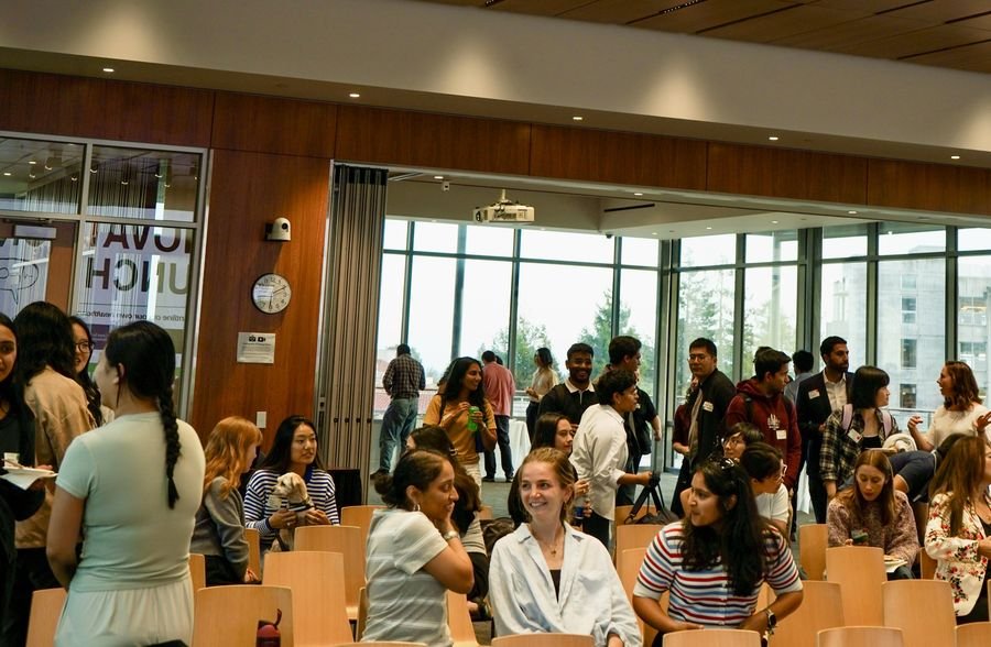 A crowded room of attendees mingling and chatting after the talks